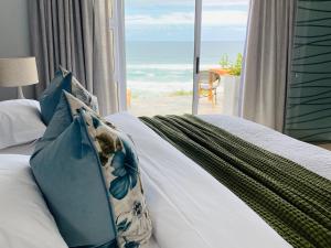 a bedroom with a bed with a view of the ocean at Mes Amis Beach Guest House in Wilderness
