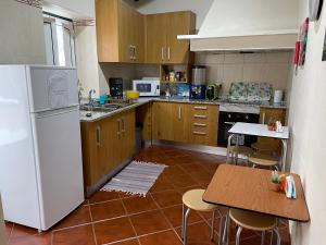 a kitchen with a white refrigerator and a table at Alojamento Porta10 in Sertã