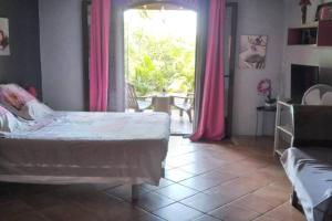 a bedroom with a bed and a window with pink curtains at Villa Baies Roses in Saint-Leu