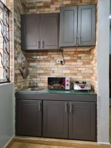 a kitchen with black cabinets and a brick wall at Unia fancy flats - studio apartment two in Kampala