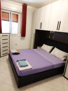 a bedroom with a purple bed with white cabinets at New Summer Apartment in Agnone Bagni