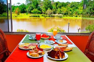 a table with breakfast food and a view of a lake at Ózera Hotel Fazenda in Prudentópolis
