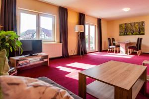ein Wohnzimmer mit einem TV und einem Tisch in der Unterkunft Hotel Bamberger Hof, garni in Eisenach