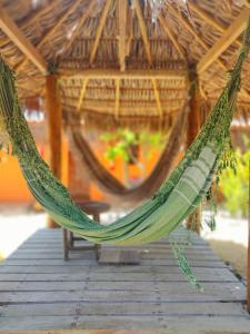 a hammock hanging from a thatched hut with a table at Pousada Kite Guajiru in Itarema