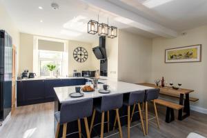 a kitchen with a large island with bar chairs at Burnside Cottage, Wark, Hexham in Hexham