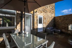 a table and chairs with an umbrella on a patio at Burnside Cottage, Wark, Hexham in Hexham