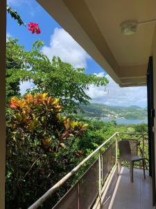 Un balcón con una silla y vistas al océano. en Top Hill appartements et dortoir - Martinique, en La Trinité