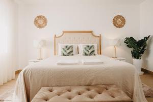a white bedroom with a large bed with a tufted headboard at Quinta Monteiro de Matos - Enoturismo in Santarém