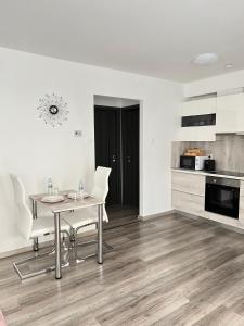 a dining room with a table and chairs and a kitchen at SunSuite Szeged in Szeged