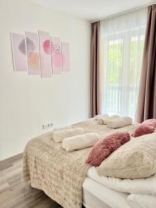 a bedroom with two beds with pillows and a window at SunSuite Szeged in Szeged