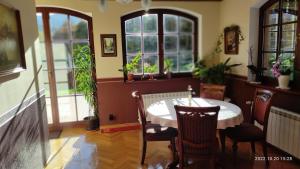 a dining room with a table and chairs and windows at Willa Leśna Polana in Szklarska Poręba