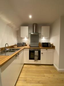 a kitchen with white cabinets and a sink at Cosy Loft Apartment in Ballycastle