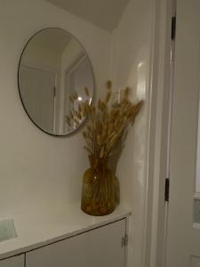 un jarrón de flores sentado en un mostrador con un espejo en Cosy Loft Apartment en Ballycastle