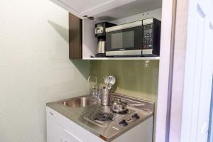 een kleine keuken met een wastafel en een magnetron bij Private Suite in North Miami in North Miami Beach