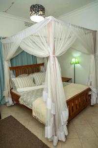 1 dormitorio con cama con dosel y cortinas blancas en Blue elephant villas en Arusha
