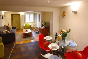 ein Wohnzimmer mit einem Glastisch und roten Stühlen in der Unterkunft Fireman's Cottage in Canterbury