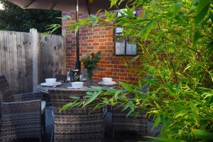 een patio met een tafel en stoelen en een bakstenen muur bij Fireman's Cottage in Canterbury