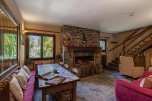 uma sala de estar com uma mesa e uma lareira de pedra em Chambres d'hôtes les Murès du Mercantour em Valdeblore