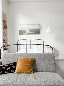 a bedroom with a bed and a couch with a pillow at Gastenverblijf De Oare Keamer Kollum Friesland in Kollum