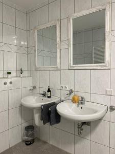 a white bathroom with two sinks and a mirror at Ferienwohnung auf dem Sonnenhang in Bad Rothenfelde