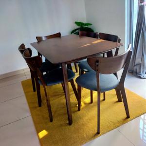 a wooden dining table and chairs on a rug at Casuarina Sea Breeze Desaru in Desaru