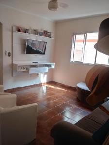 sala de estar con TV y suelo de baldosa. en Canto do Forte da Ivone, en Praia Grande