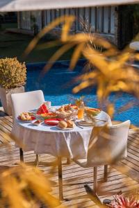 una mesa con comida junto a una piscina en Pousada Boutique Itaipava, en Itaipava