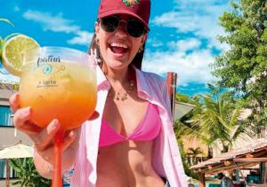 a woman in a pink bikini holding a drink at Pousada Patuá do Morro in Morro de São Paulo