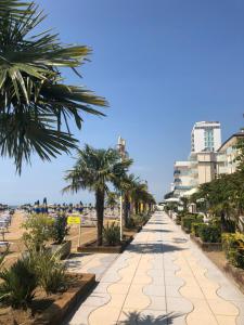 einen Fußweg entlang des Strandes mit Palmen und Gebäuden in der Unterkunft Hotel Marco Polo in Lido di Jesolo