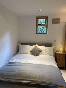 a bed with white sheets and a window in a bedroom at Cosy 1 bedroom country lodge with free parking in Watlington