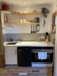 a small kitchen with a sink and a stove at Cosy 1 bedroom country lodge with free parking in Watlington