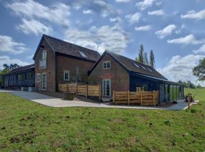 ein großes Backsteinhaus mit einem Feld davor in der Unterkunft Lodge Farm in Freston