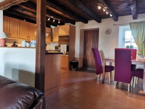 a kitchen and dining room with a table and purple chairs at la Petite Maison De Vacances in Oradour-Saint-Genest