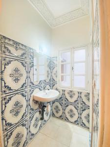 uma casa de banho com paredes em azulejos azuis e brancos e um lavatório. em WELKAM Home & Coworking em Essaouira