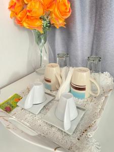 a table with plates and cups and a vase with orange roses at Best Rooms- Quarto 2 Plateau in Praia