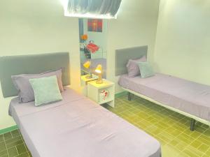 a room with two beds and a table with a lamp at Best Rooms- Quarto 2 Plateau in Praia