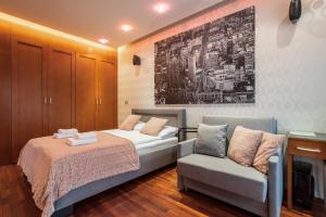 a bedroom with a bed and a couch and a chair at Broadway - Neptun Park by OneApartments in Gdańsk