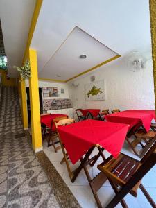 a restaurant with red tables and chairs with red umbrellas at Pousada Recanto da Ana Alice in Abraão