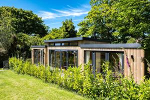 a wooden greenhouse in a garden with plants at Chi Lowarth in Helston