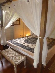 a bed with a canopy and a bench in a room at Caribbean Ashanti Lodge in Trois-Rivières