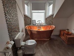a bathroom with a copper tub and a toilet at Seaclusion in Saint Monance