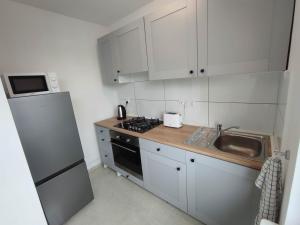 una pequeña cocina con armarios blancos y fregadero en ***Casablanca Apartament*** - 40m² ✓, en Rybnik