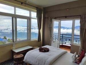 a bedroom with a bed and a balcony with windows at Hotel High Ground Inn Sarangkot in Pokhara