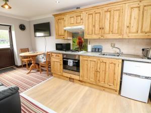 cocina con armarios de madera, fregadero y mesa en Ashford Cottage, en Bakewell
