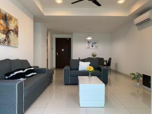 uma sala de estar com dois sofás azuis e uma mesa em KSL Desplanade By Antlerzone em Johor Bahru