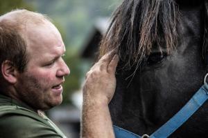 Un uomo in piedi accanto a un cavallo nero di Ferienhof Felder a Bezau