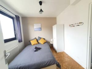 um quarto com uma cama com almofadas amarelas e uma janela em L'Orchidée - Cosy Flat, 20min From Paris em Drancy