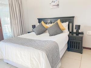 een slaapkamer met een groot bed met witte lakens en kussens bij Akani Guest House in White River