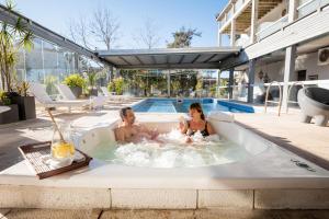 un hombre y una mujer en un jacuzzi en una piscina en Hotel Valeria Apart & Hotel Spa en Valeria del Mar