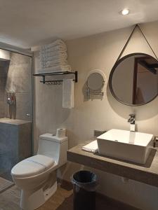 bagno con servizi igienici, lavandino e specchio di Hotel Del Valle a Tecozautla